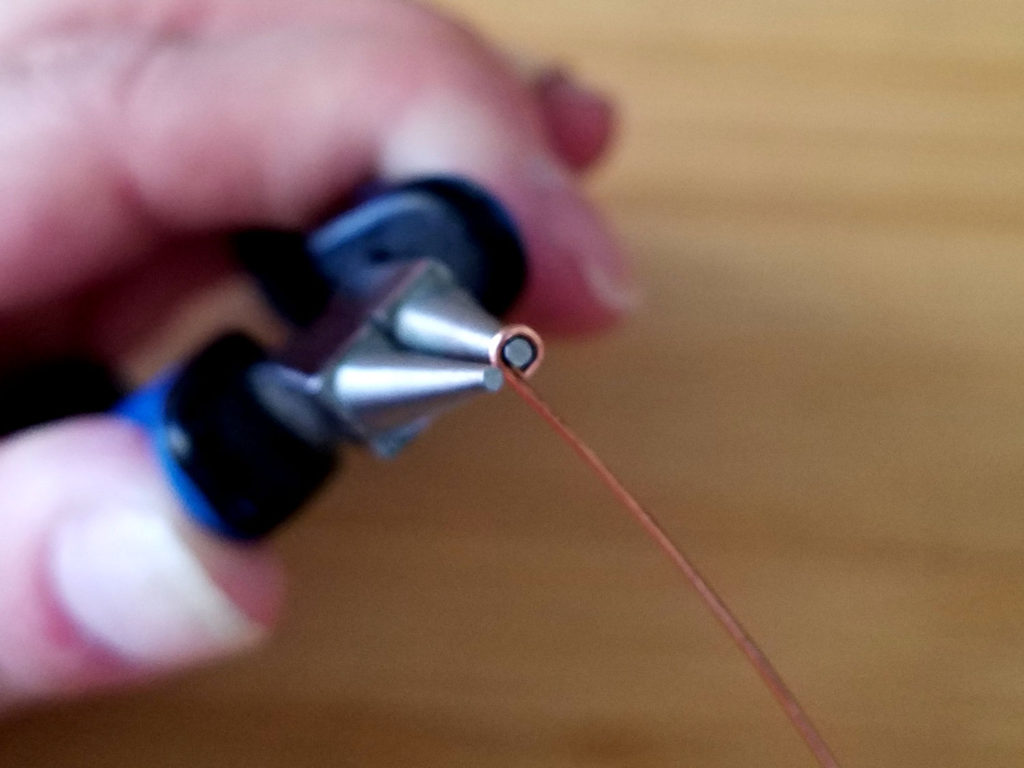 Step 5 - Reposition your pliers so one jaw is within the small loop and the other is resting against the straight length of your wire, as shown.