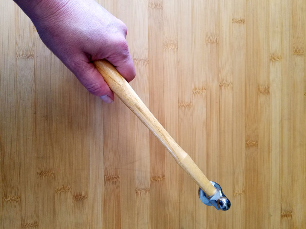 This image shows the correct way to hold a chasing hammer, from the end of the handle, which is shaped to fit comfortably in the palm of your hand. 