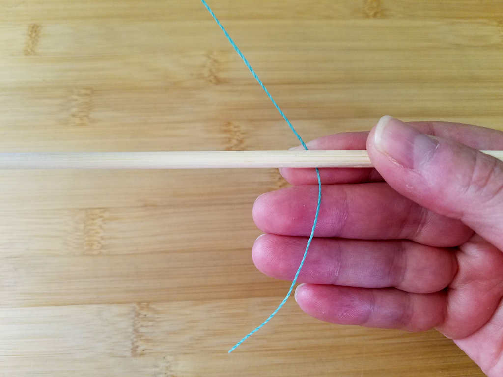 To begin the Modified Soumak weave, hold one core wire and place the weaving wire behind the core with the tail pointing down and the working wire above the core wire, as shown.