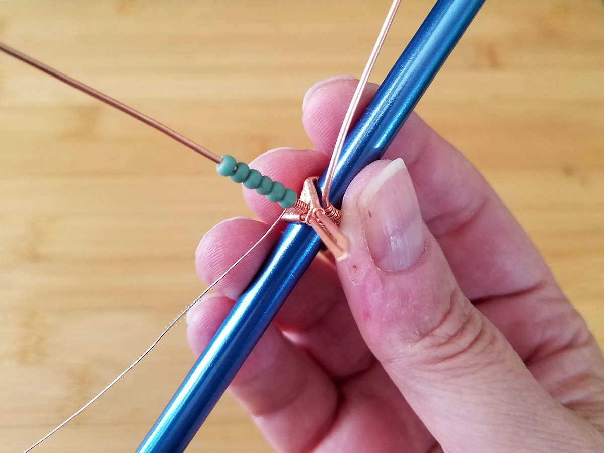 Several seed beads have been threaded onto the central core wire in this image. 