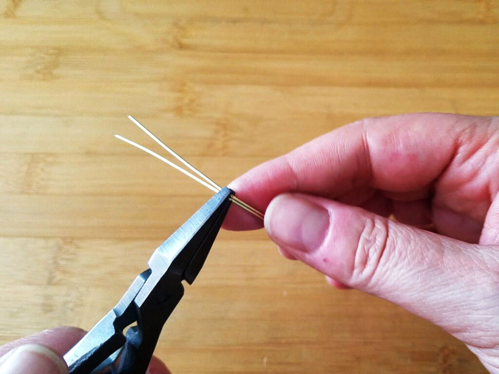 Using flat nose pliers to bend the wires at the center mark