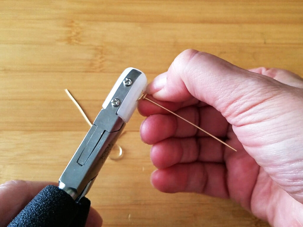 Gripping the loop with nylon jaw pliers while securing the loop by wrapping the wire tail around the center core wire