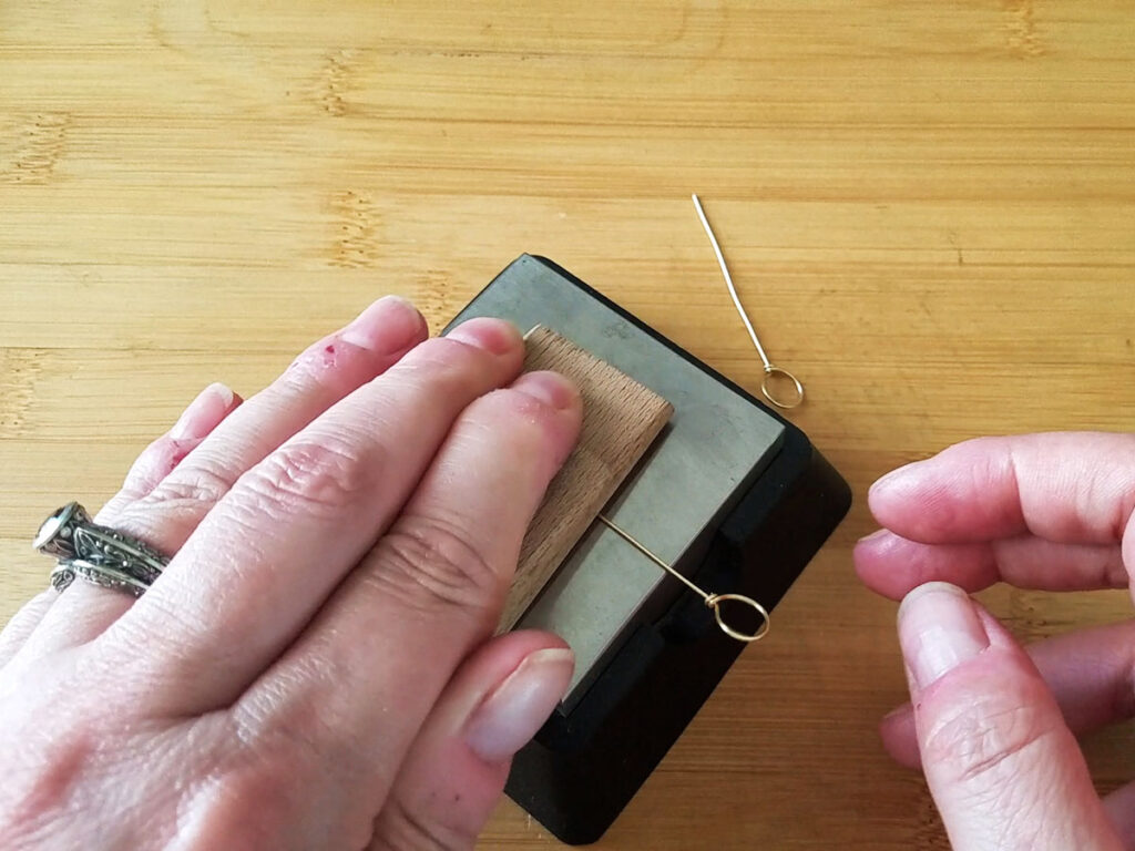 Using a steel bench block and a piece of hardwood to straighten and harden the center core wire