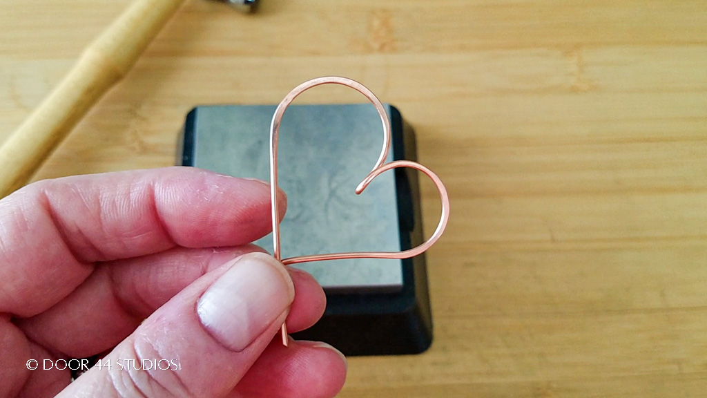 The wire heart pendant after hammering the second curve of the heart shape